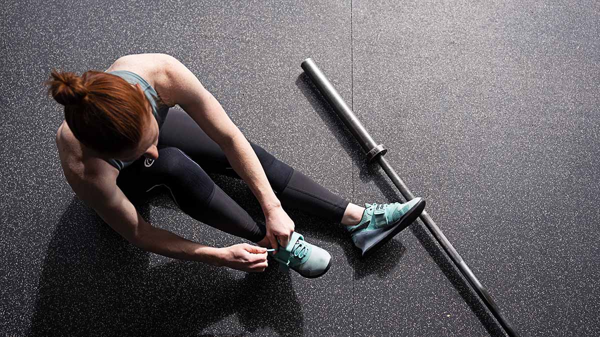 Strength Guide Chapter 2 Female Weightlifter Tying Shoes Preparing For A Strength Training Workout