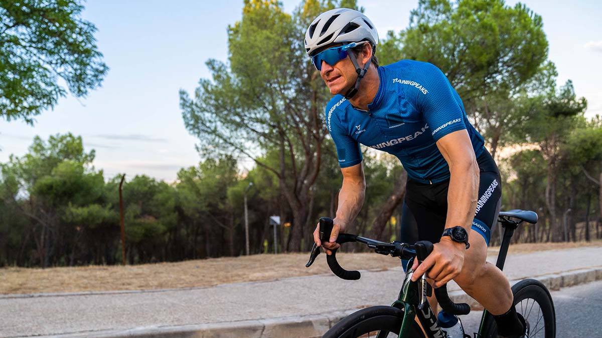A Male Rider In A Trainingpeaks Cycling Kit Pedaling Out Of The Saddle On A Road In Spain